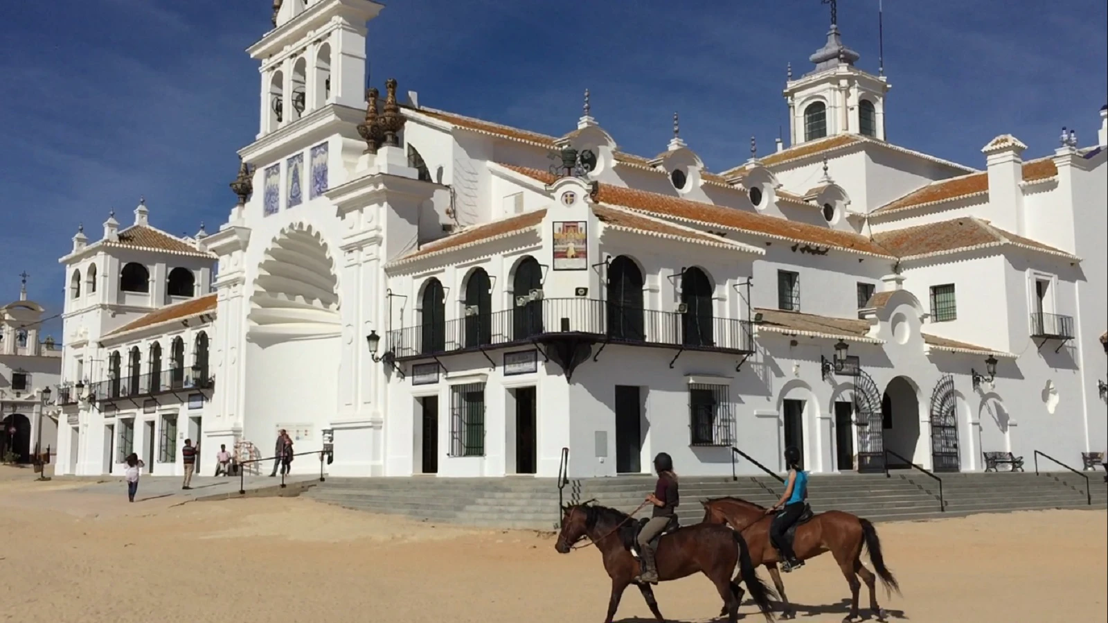 two riders on horses in front of the church of El Rocio